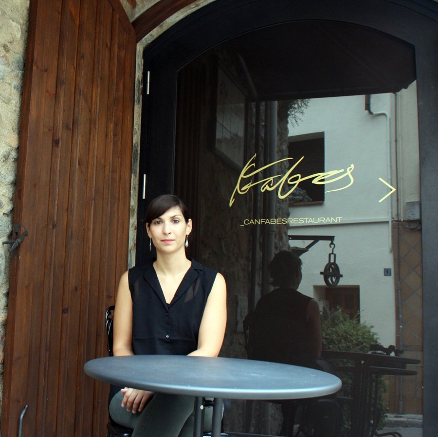 Regina Santamaria sentada davant l'entrada del restaurant