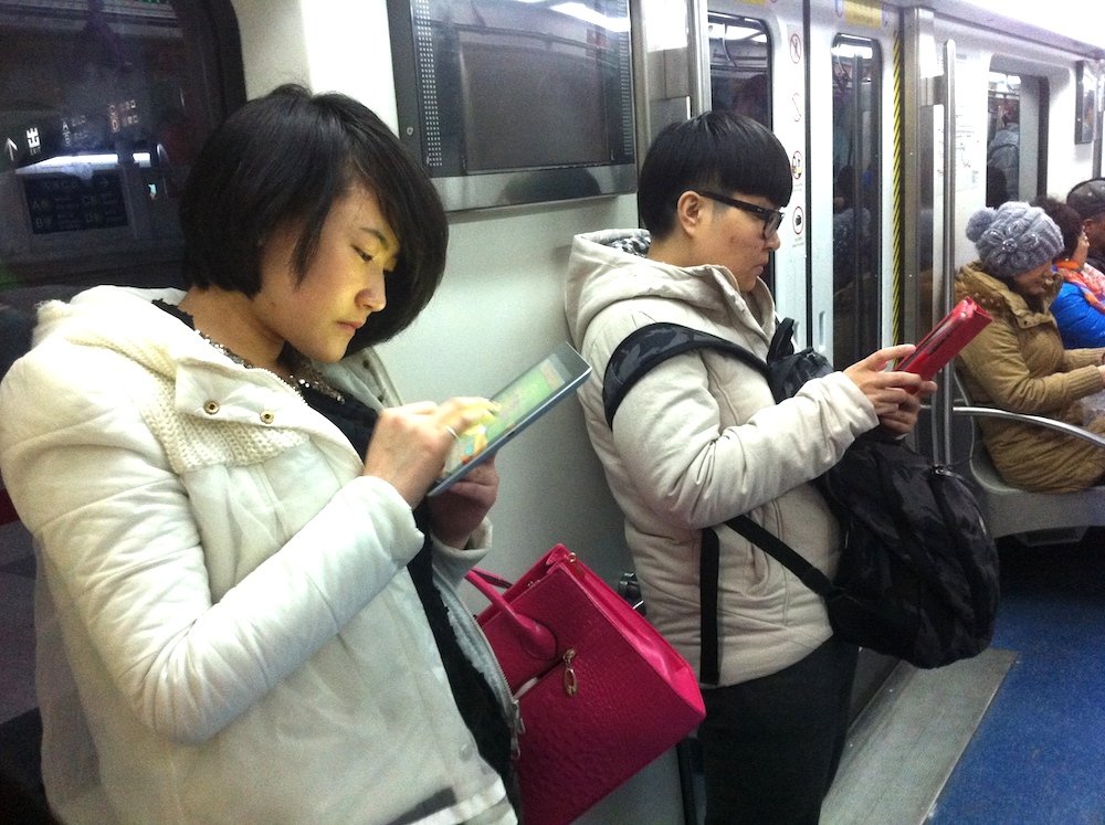 Dos chinas consultando su tablet al metro
