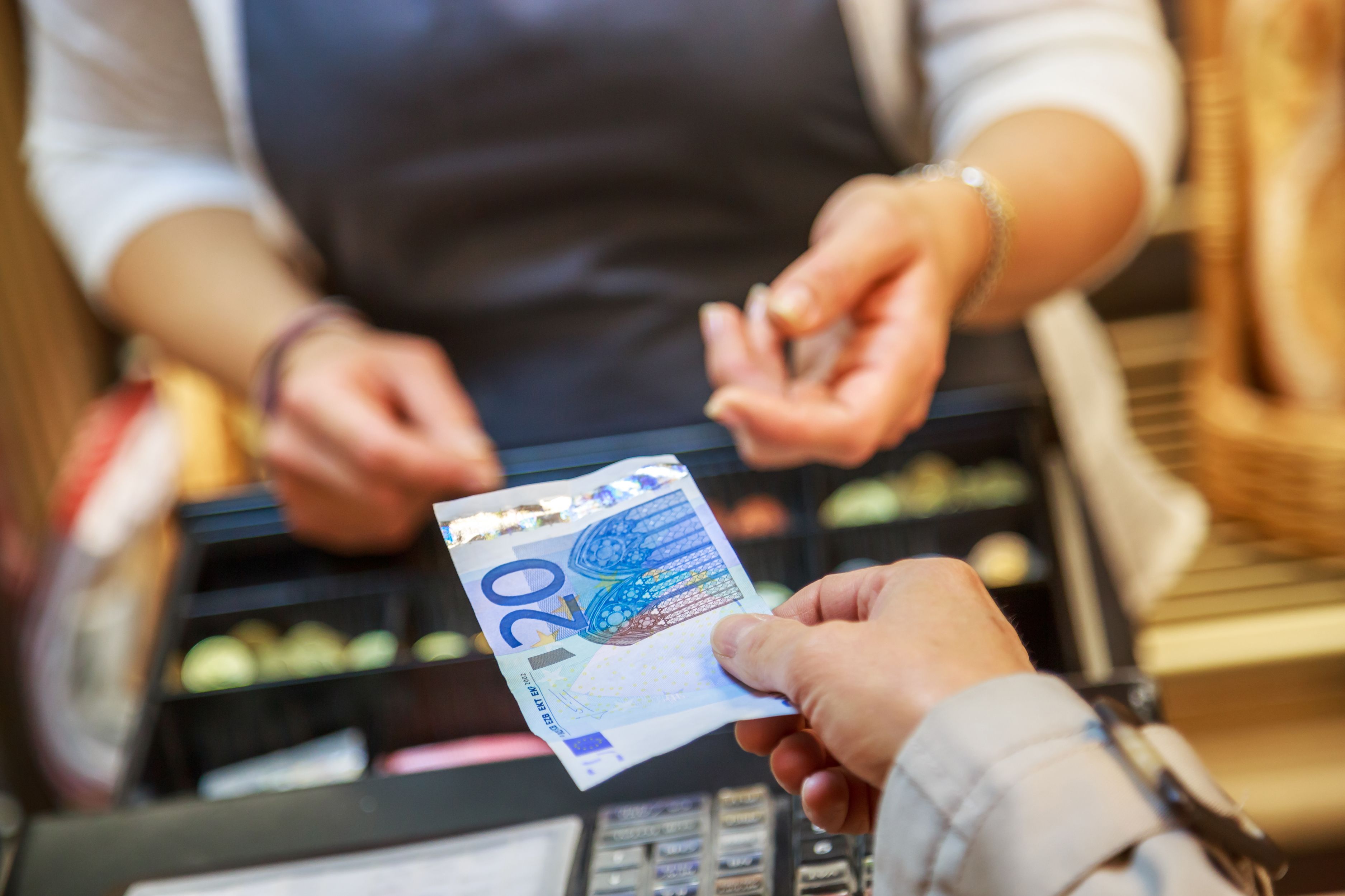 Una persona paga en efectivo a un comerç | iStock Una persona paga en efectivo a un comerç | iStock