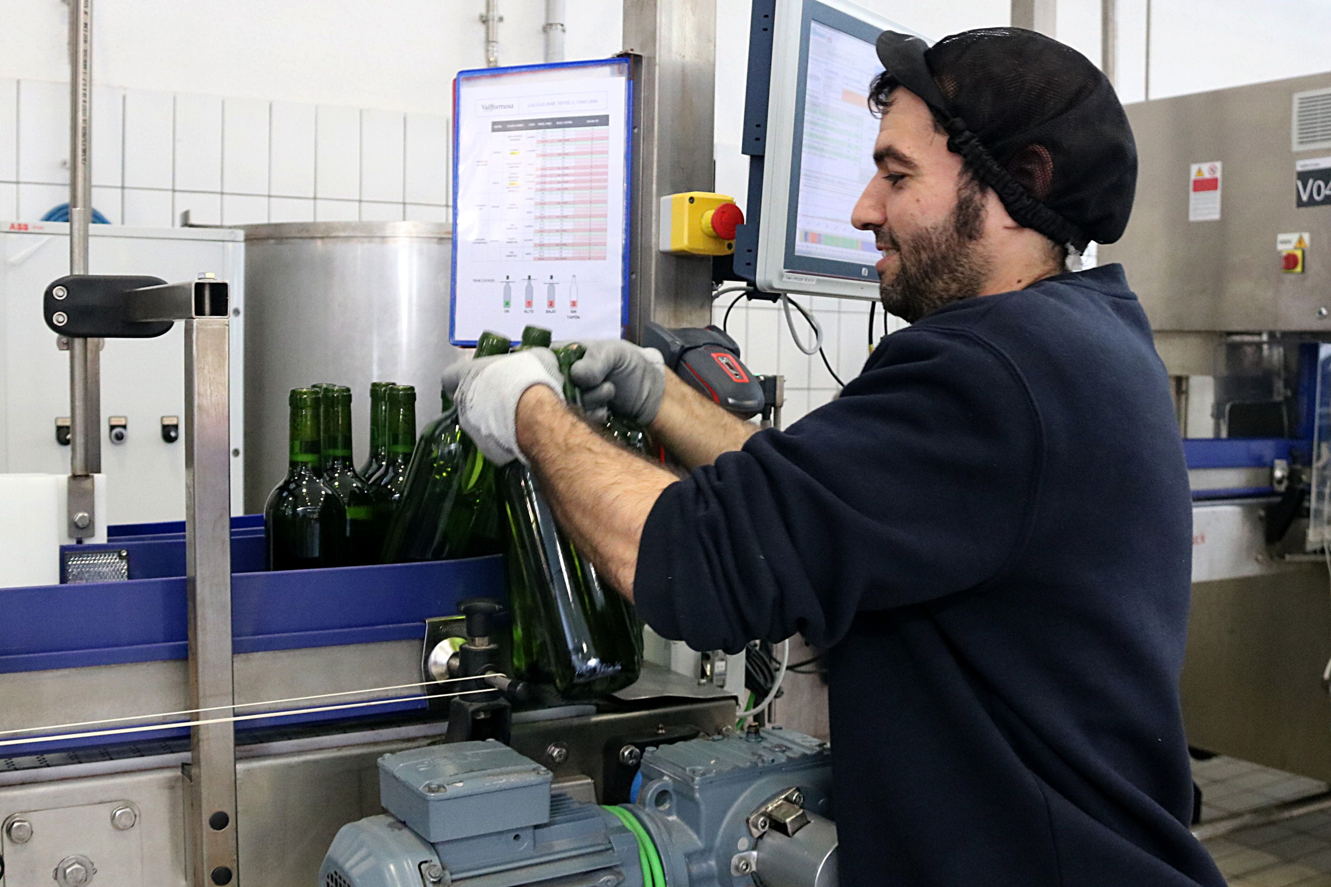 Un trabajador manipulando botellas de vino en una cadena de producción | ACN