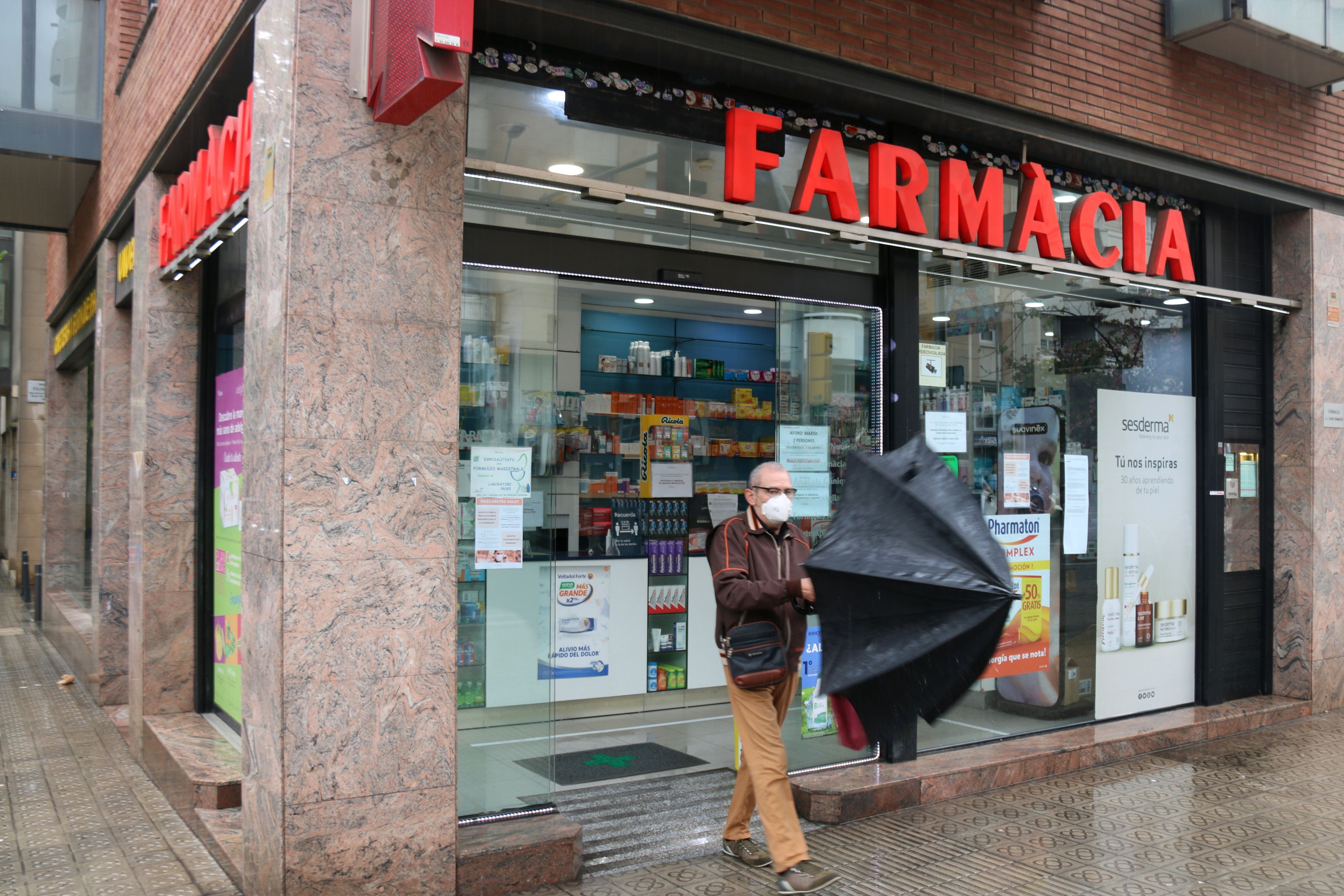 Un home obre un paraigües a la sortida d'una farmàcia | Miquel Codolar (ACN) Un home obre un paraigües a la sortida d'una farmàcia | Miquel Codolar (ACN)
