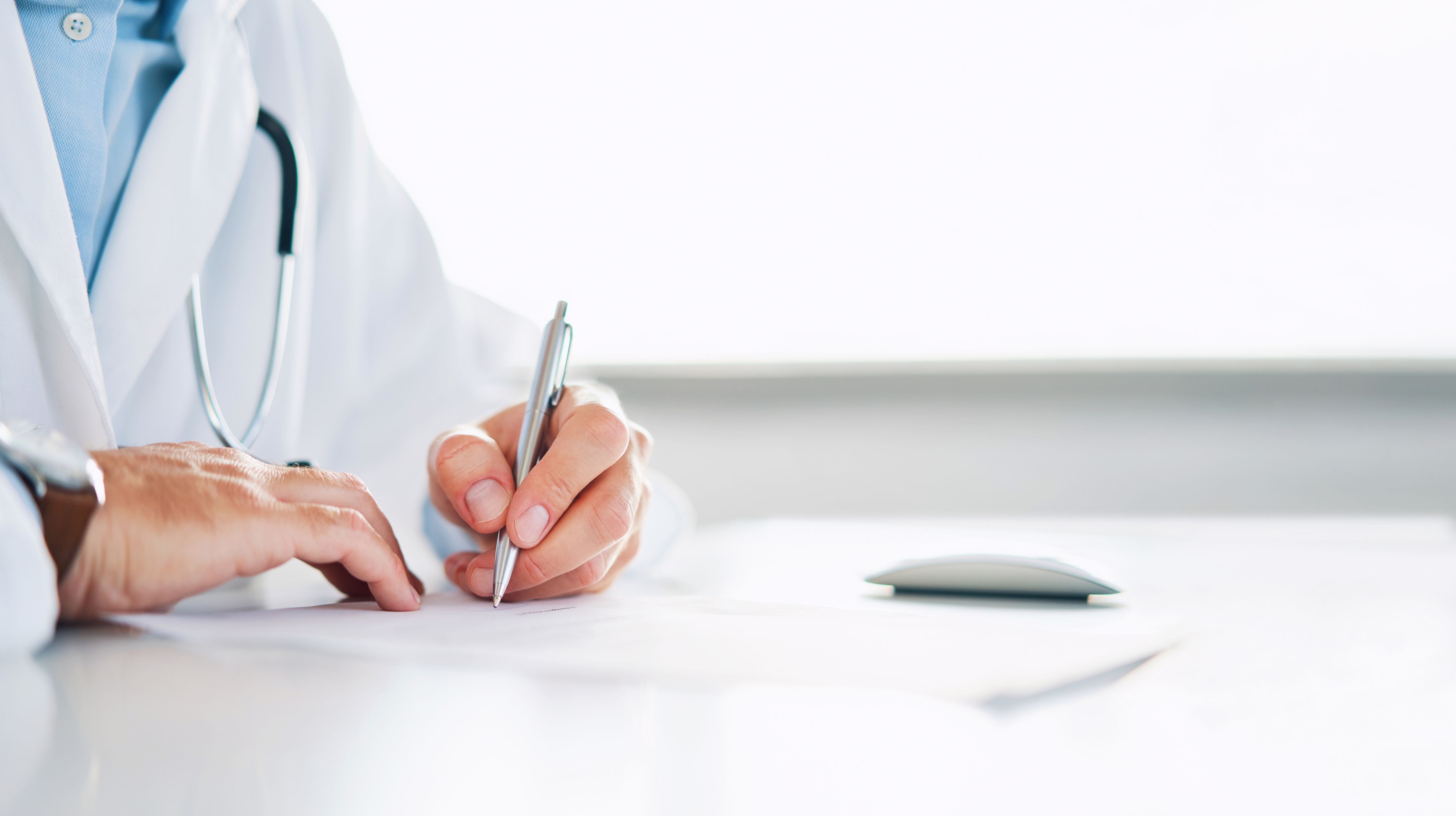 Imagen de un médico firmando un documento | iStock