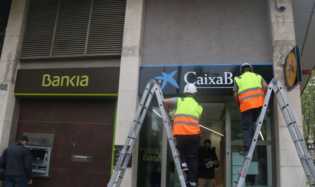 Dos operarios realizan el cambio de nomenclatura de una oficina de Bankia | ACN Dos operarios realizan el cambio de nomenclatura de una oficina de Bankia | ACN