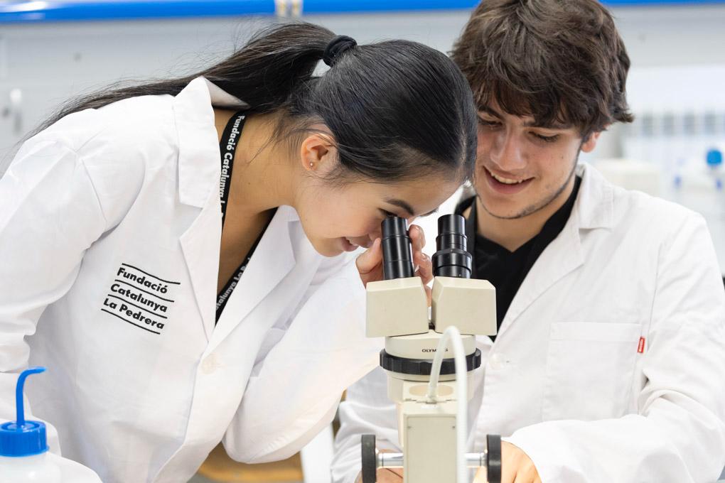 Dos joves estudien a través d'un microscopi | Fundació Catalunya La Pedrera
