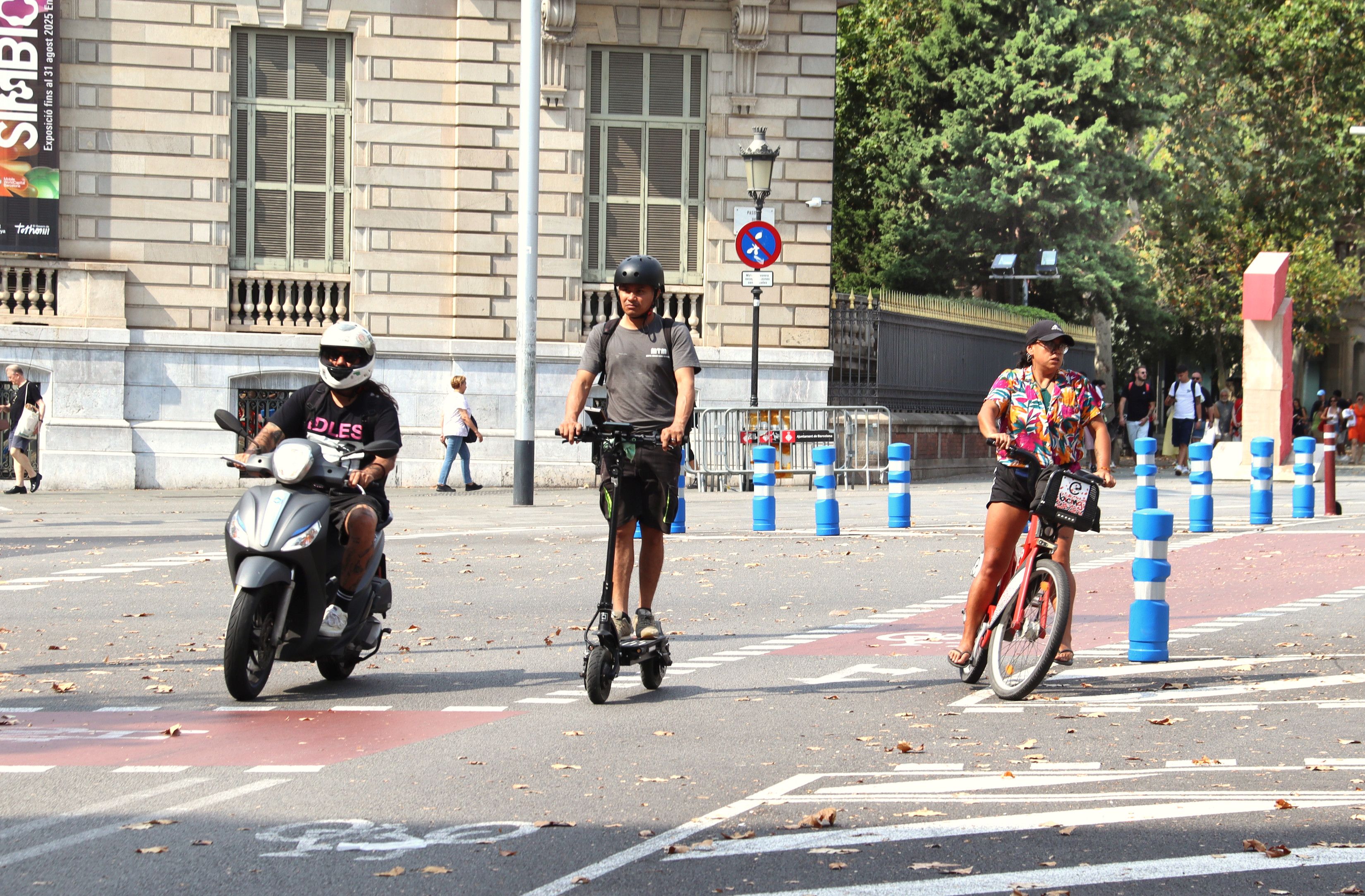 Una moto, un patinete y una bici circulan por una calle de Barcelona, en un tramo donde hay carril bici sin protección | Maria Rodríguez / ACN