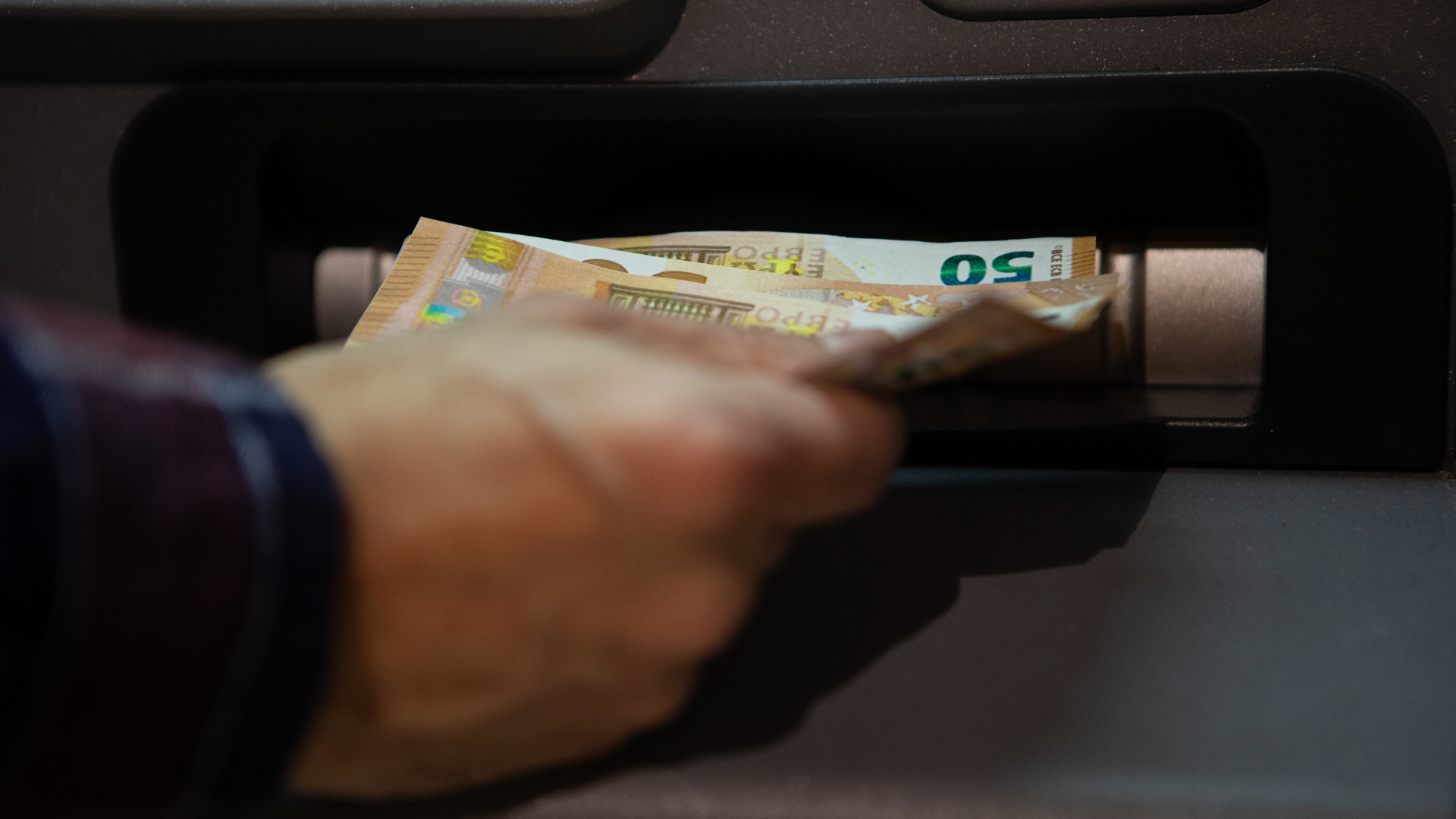 Una persona retira dinero de un cajero automático | Unión Europea (ACN)