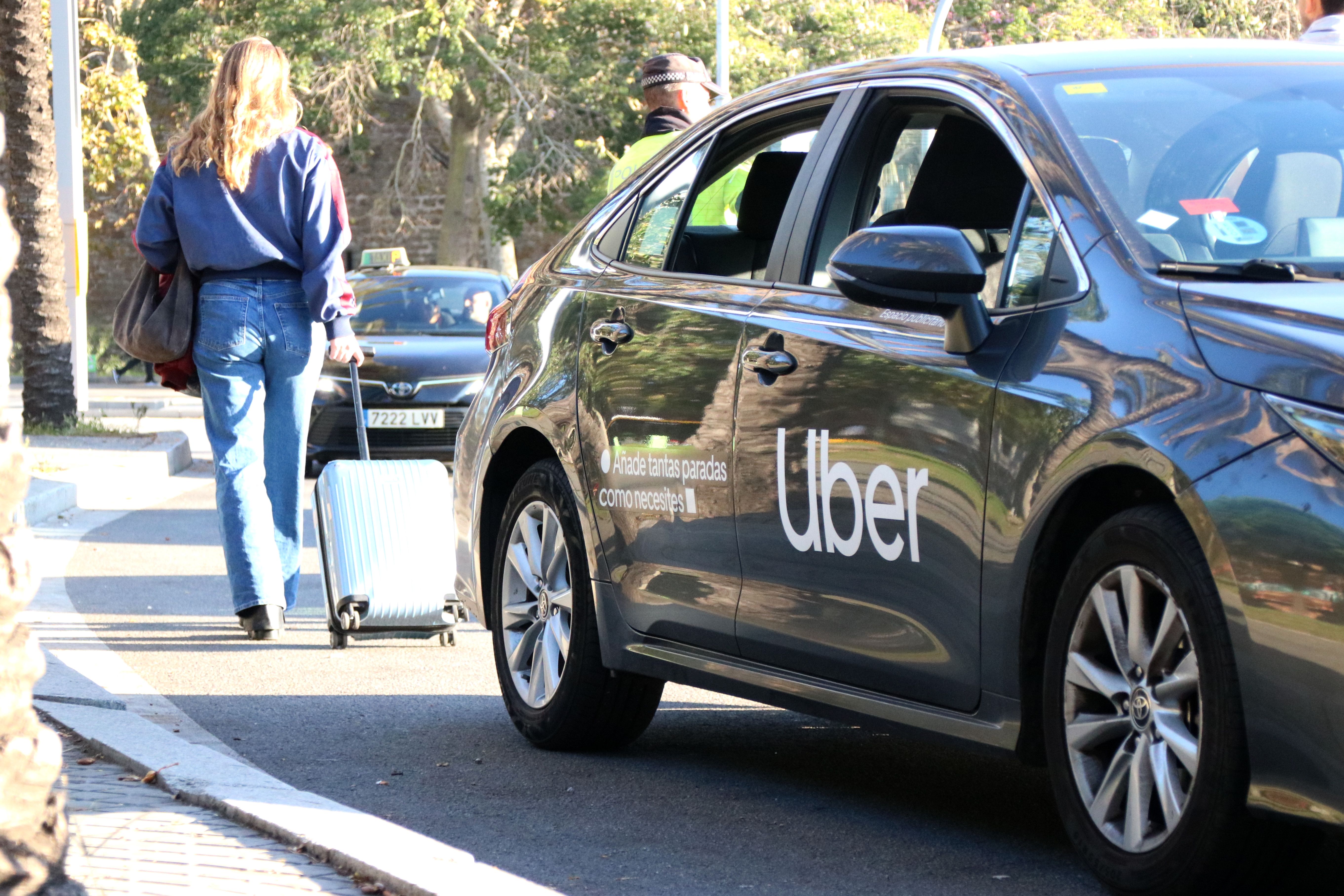 Una passatgera abandona el vehicle Uber immobilitzat per un agent de la Guàrdia Urbana i va a la cerca d'un taxi | Albert Hernàndez (ACN) Una passatgera abandona el vehicle Uber immobilitzat per un agent de la Guàrdia Urbana i va a la cerca d'un taxi | Albert Hernàndez (ACN)