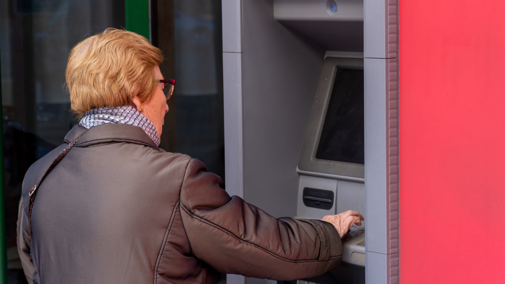 Una mujer mayor retira dinero de un cajero automático | iStock