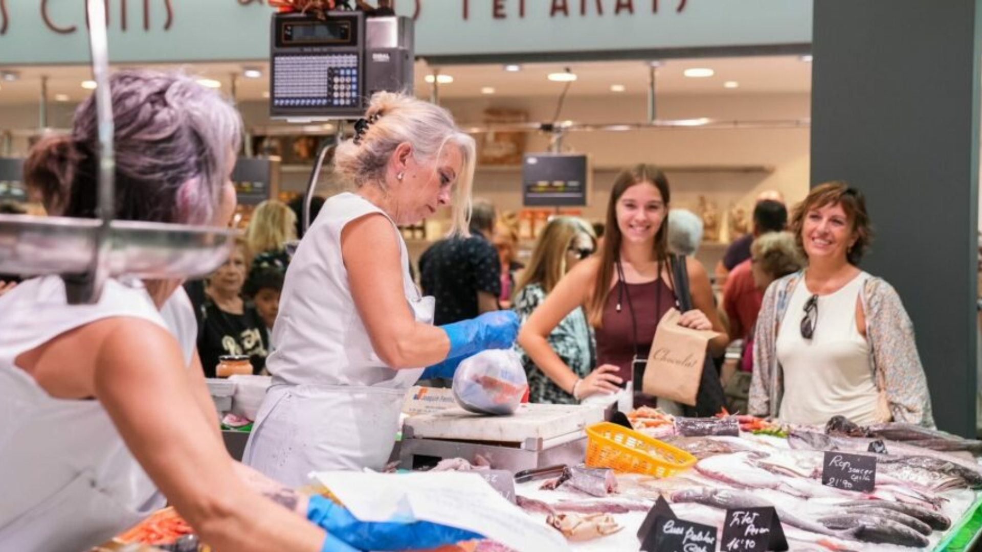 Una peixateria del Mercat de Sant Andreu on es veu dues treballadores atenent dues clientes | Mariona Gil (Imatges Barcelona)