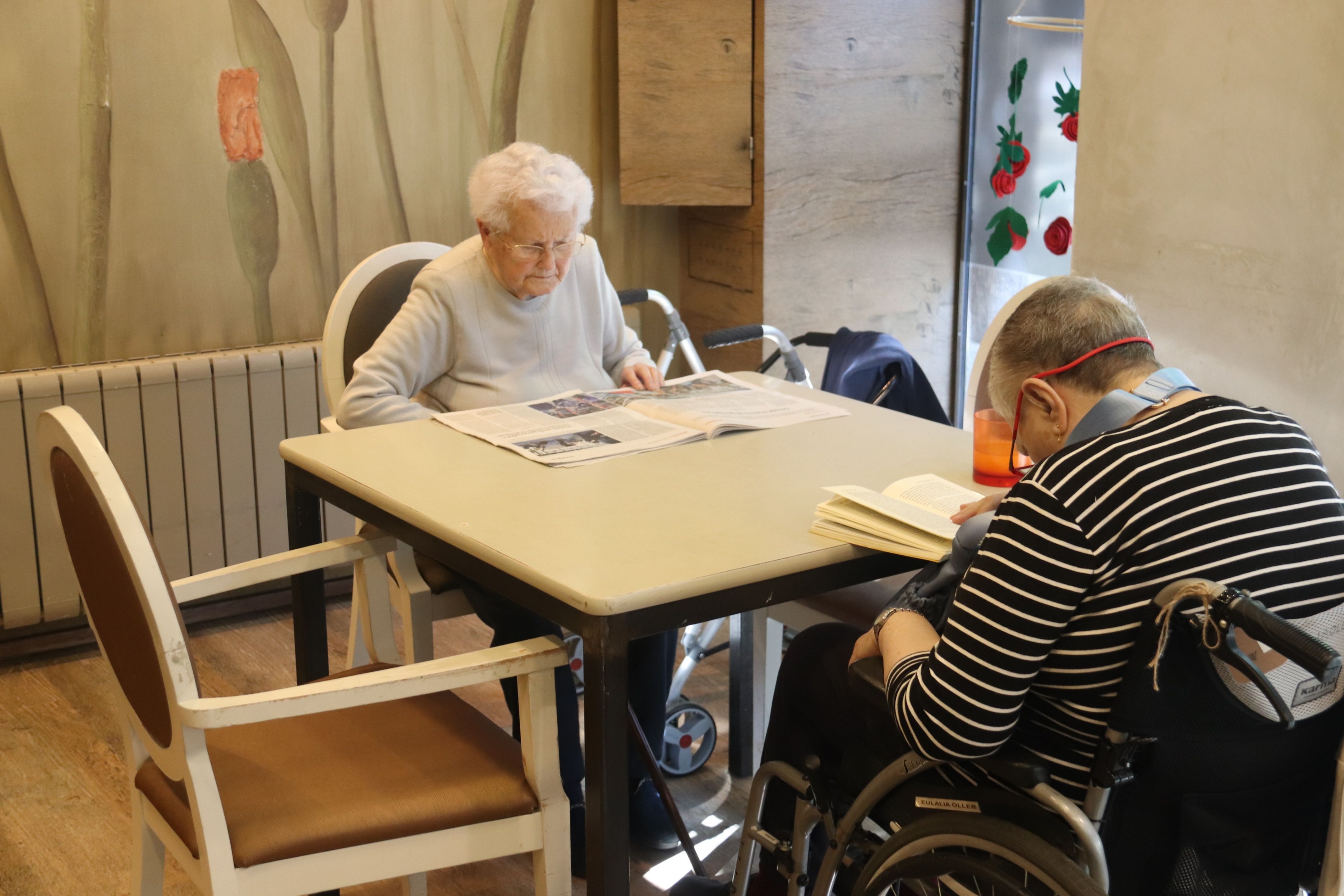 Dues usuàries de la residència de Can Regàs de Girona llegeixen sota la llum d'un fluorescent hores després de recuperar-se el servei | Aleix Freixas (ACN)