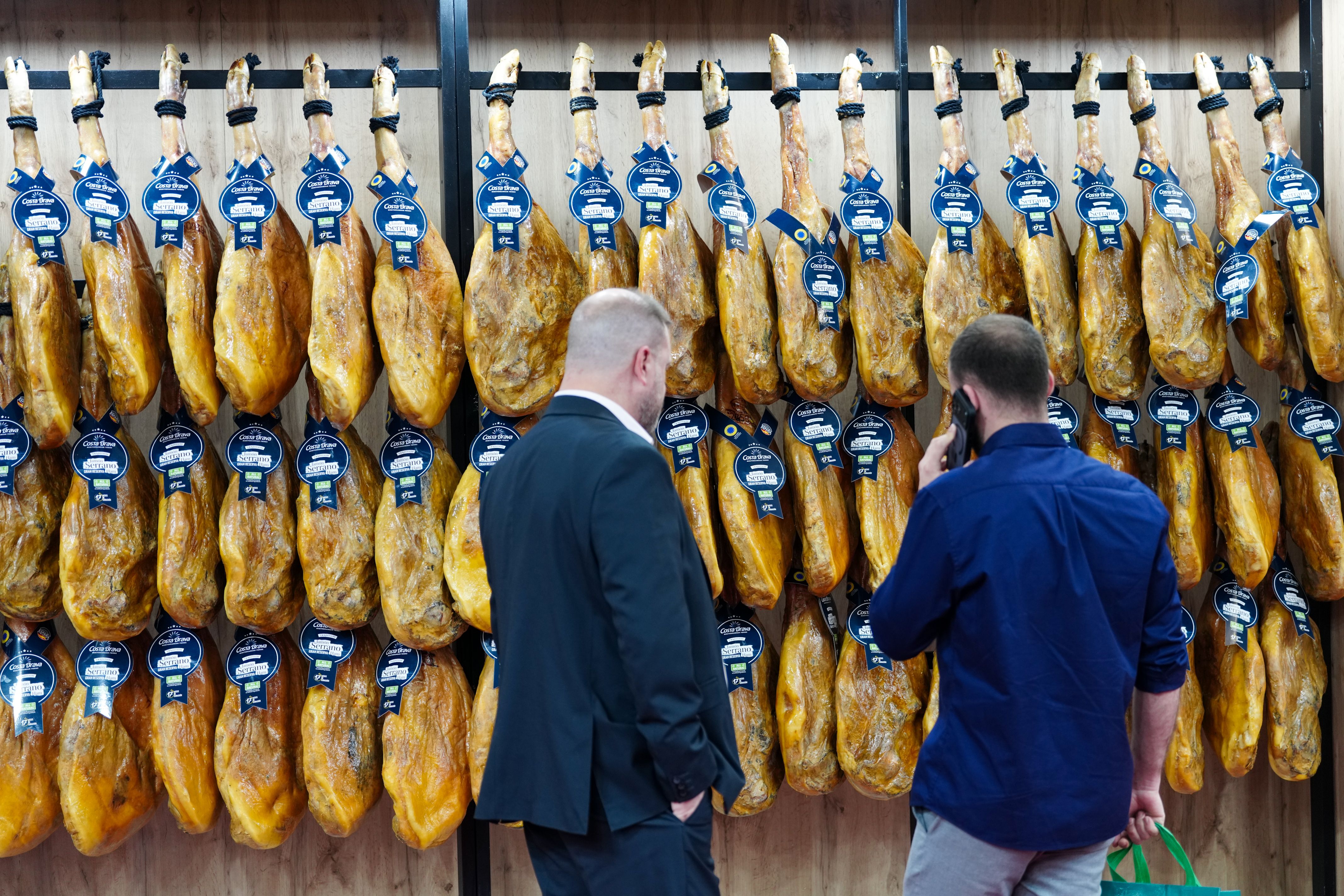 Dos visitants en un estand de pernils a l'Alimentaria + Hostelco | ACN