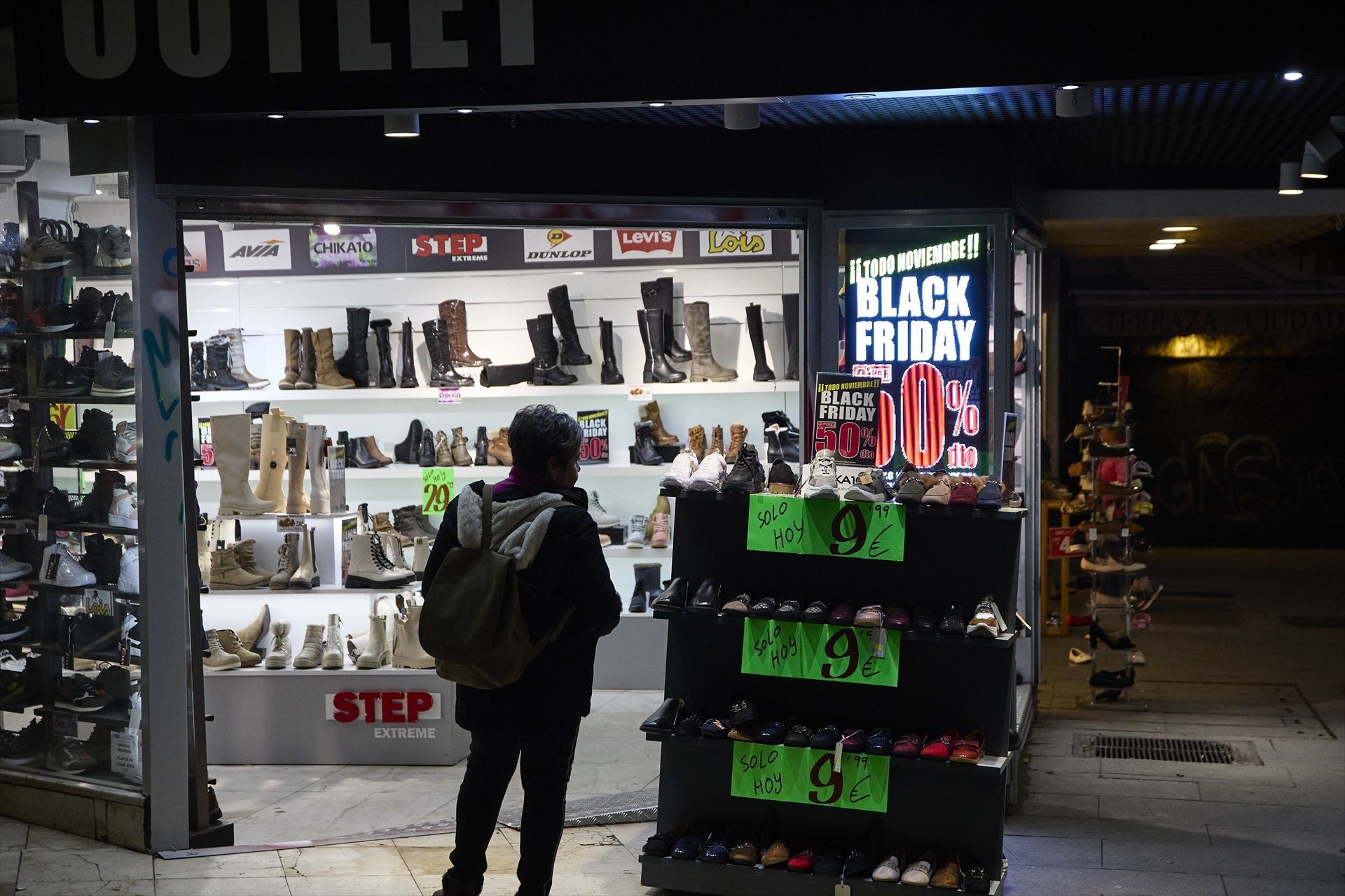 Varias personas pasan por delante de los comercios que anuncian los descuentos del Black Friday | Jesús Hellín (Europa Press)