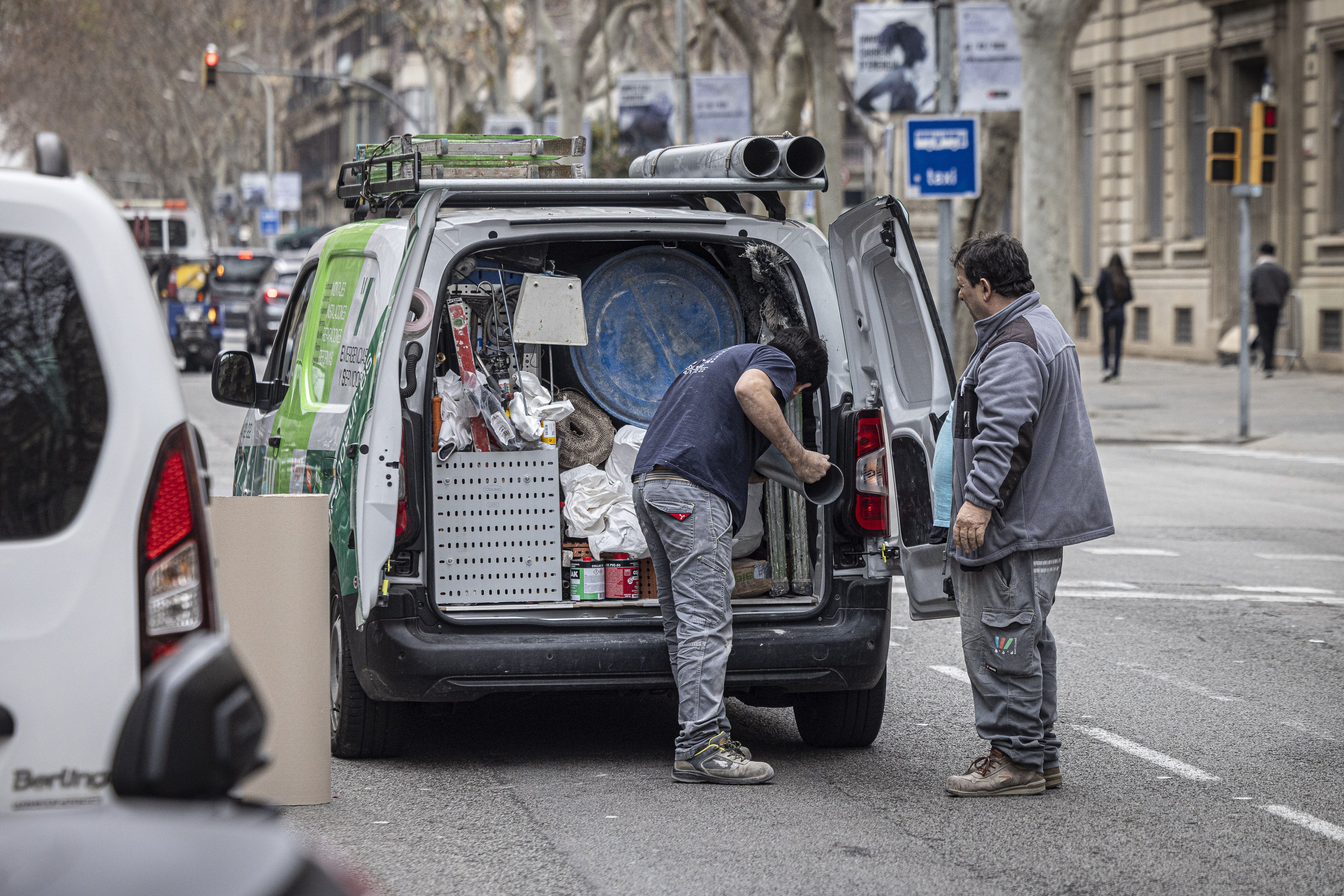 Unos trabajadores cargan una furgoneta con material de construcción | Jordi Borràs (ACN)