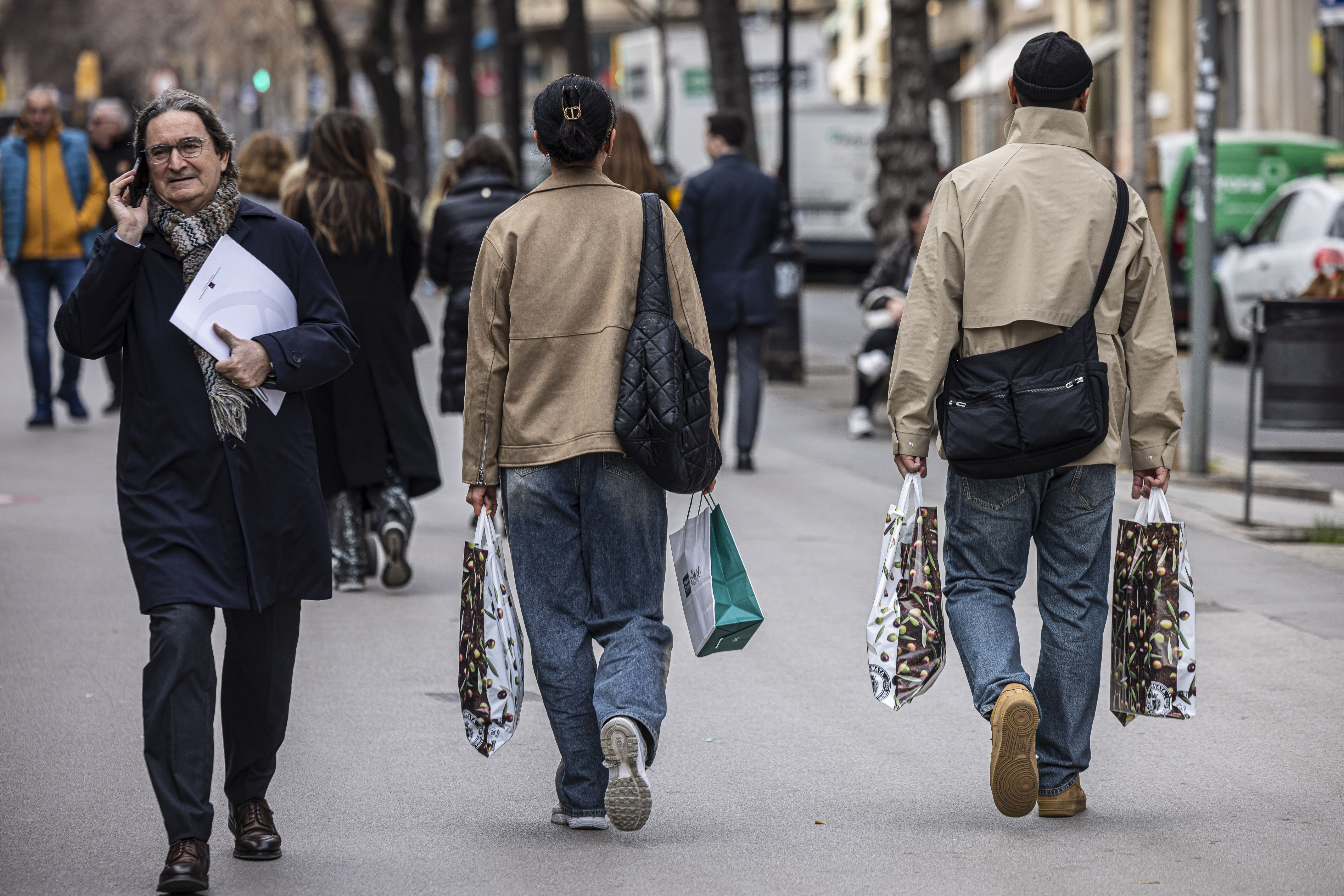 Dos turistes passejant amb bosses per un carrer comercial de Barcelona | Jordi Borràs (ACN)