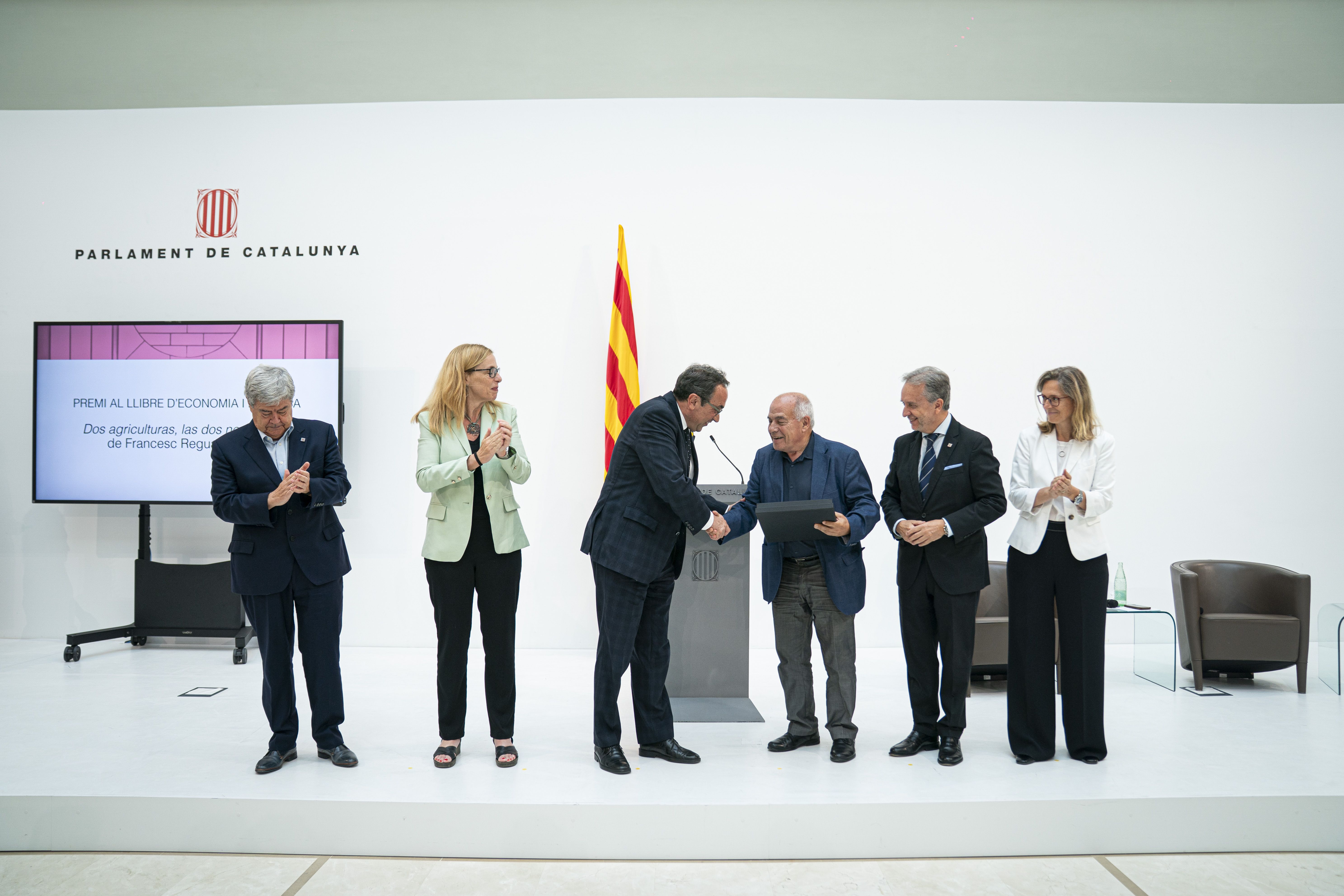 L'economista i col·laborador de VIA Empresa, Francesc Reguant, rep el seu premi en mans del president del Parlament, Josep Rull, i acompanyat pels economistes i col·laboradors de VIA Empresa, Guillem López Casasnovas i Carme Poveda, a més d'Àngels Fitó i Carlos Puig de Travy, vicedegana i degà del Col·legi d'Economistes de Catalunya | Cedida