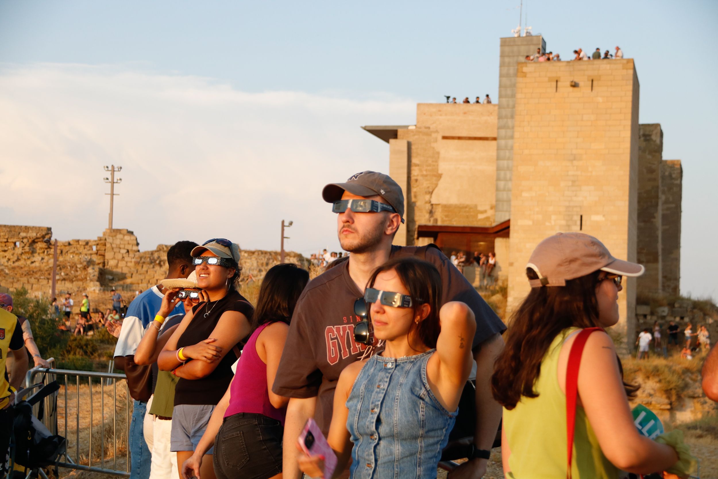 Varias personas observan el eclipse con el Castell de la Suda de Lleida de fondo | Marc Codinas (ACN)