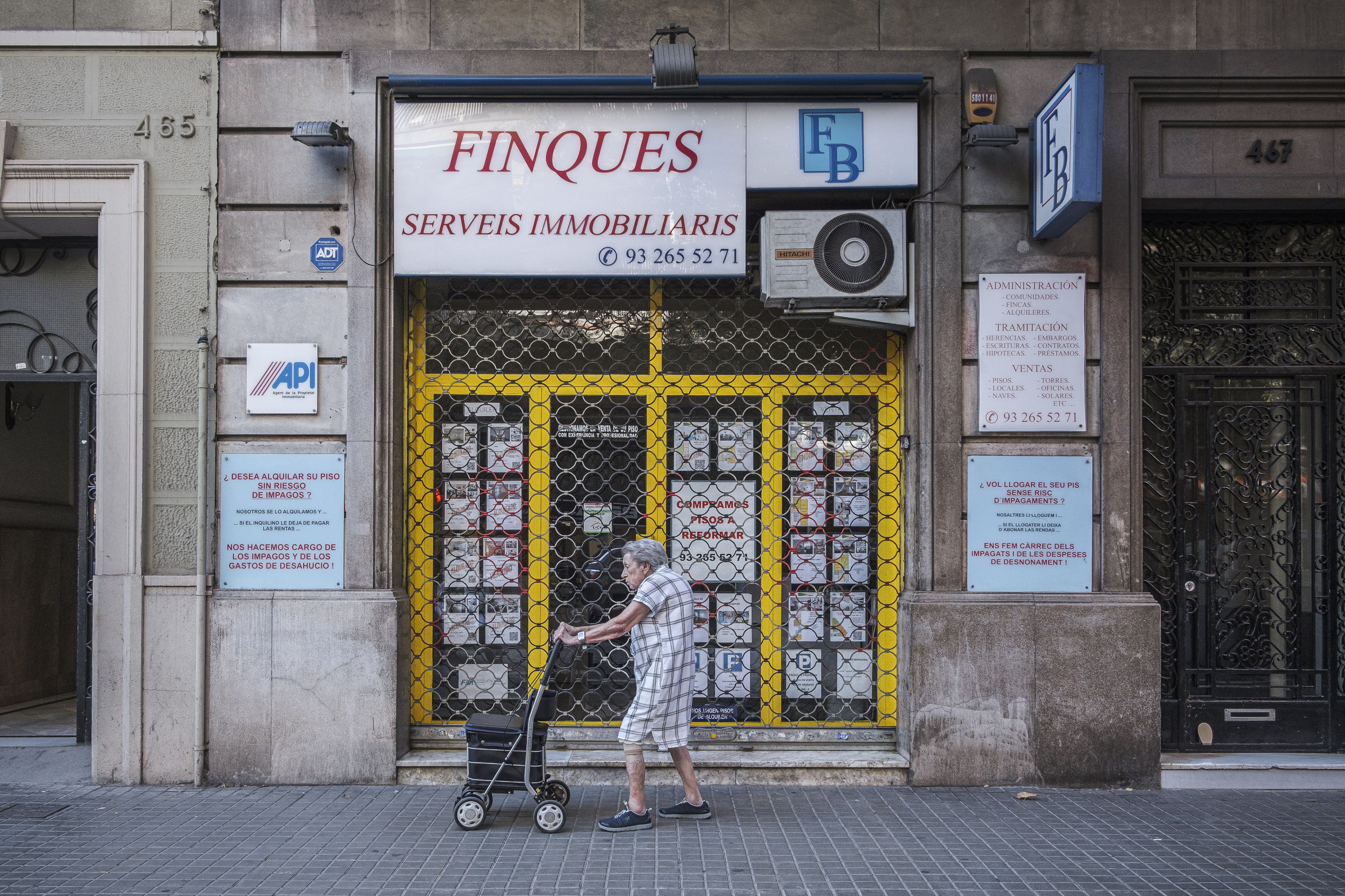 Una dona passejant davant d'una immobiliària on s'anuncien habitatges | Jordi Borràs (ACN) Una dona passejant davant d'una immobiliària on s'anuncien habitatges | Jordi Borràs (ACN)
