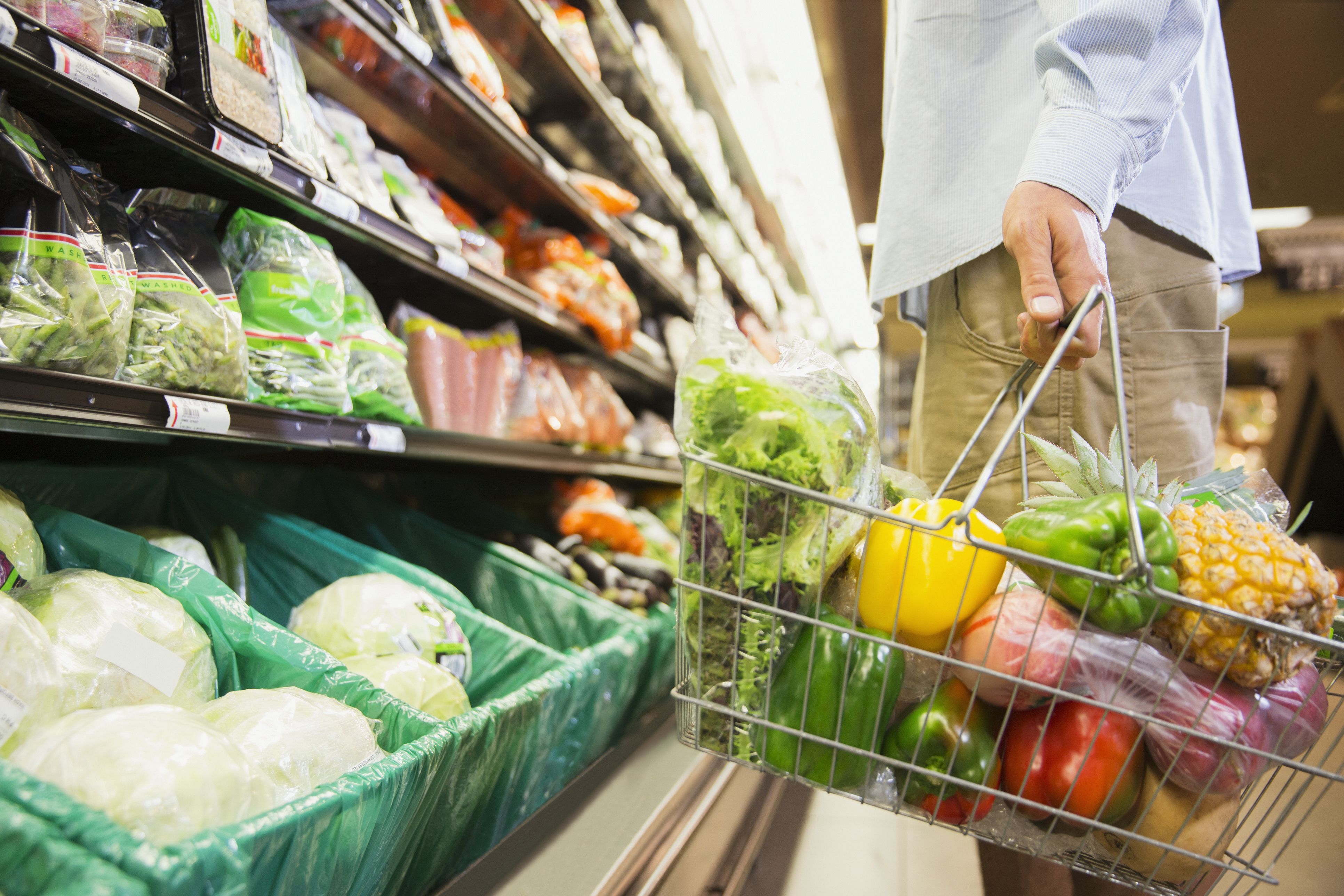 Un home sosté la cistella de la compra a un supermercat | iStock