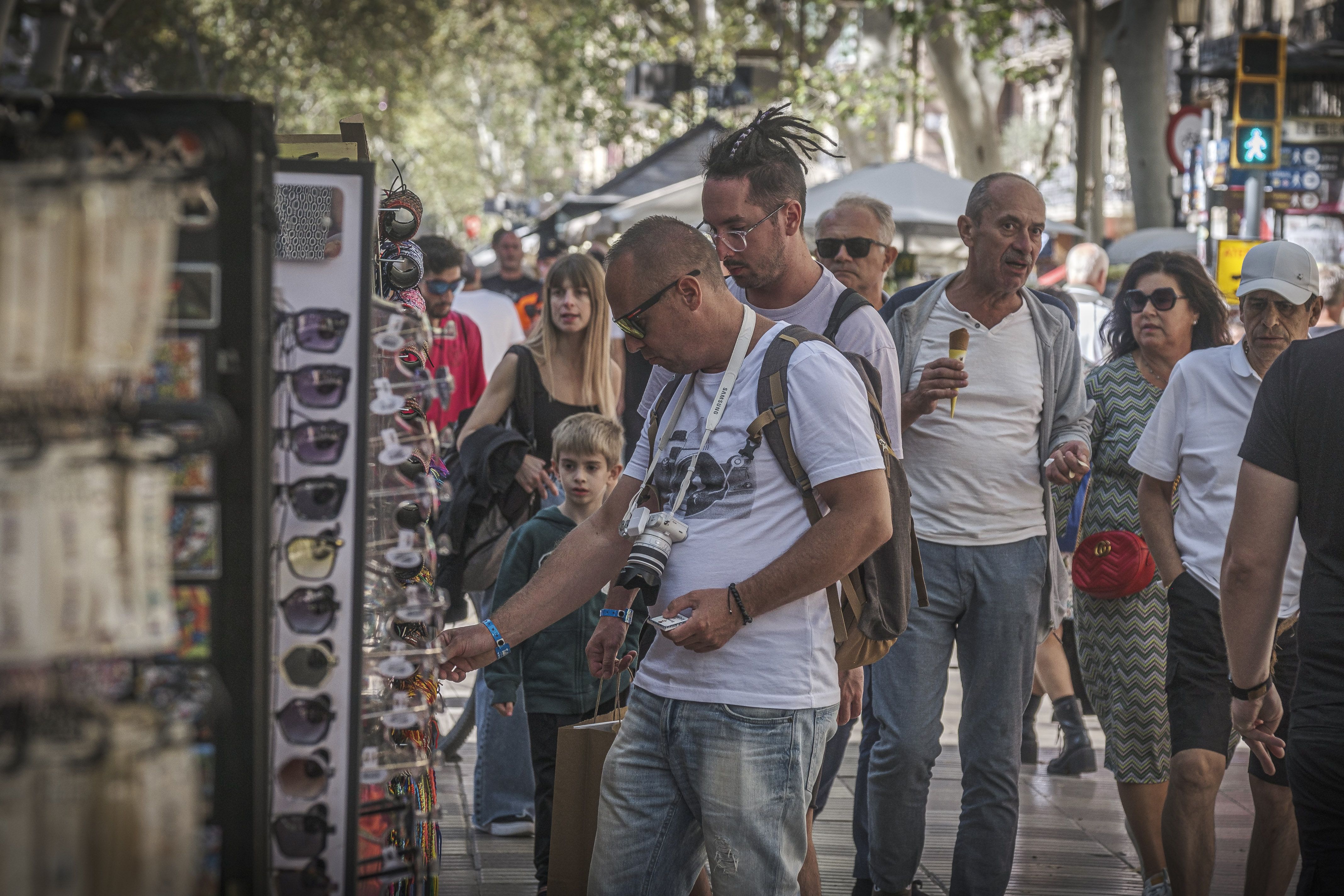 Un turista mirant un producte en un quiosc de la Rambla de Barcelona | Jordi Borràs (ACN) Un turista mirant un producte en un quiosc de la Rambla de Barcelona | Jordi Borràs (ACN)