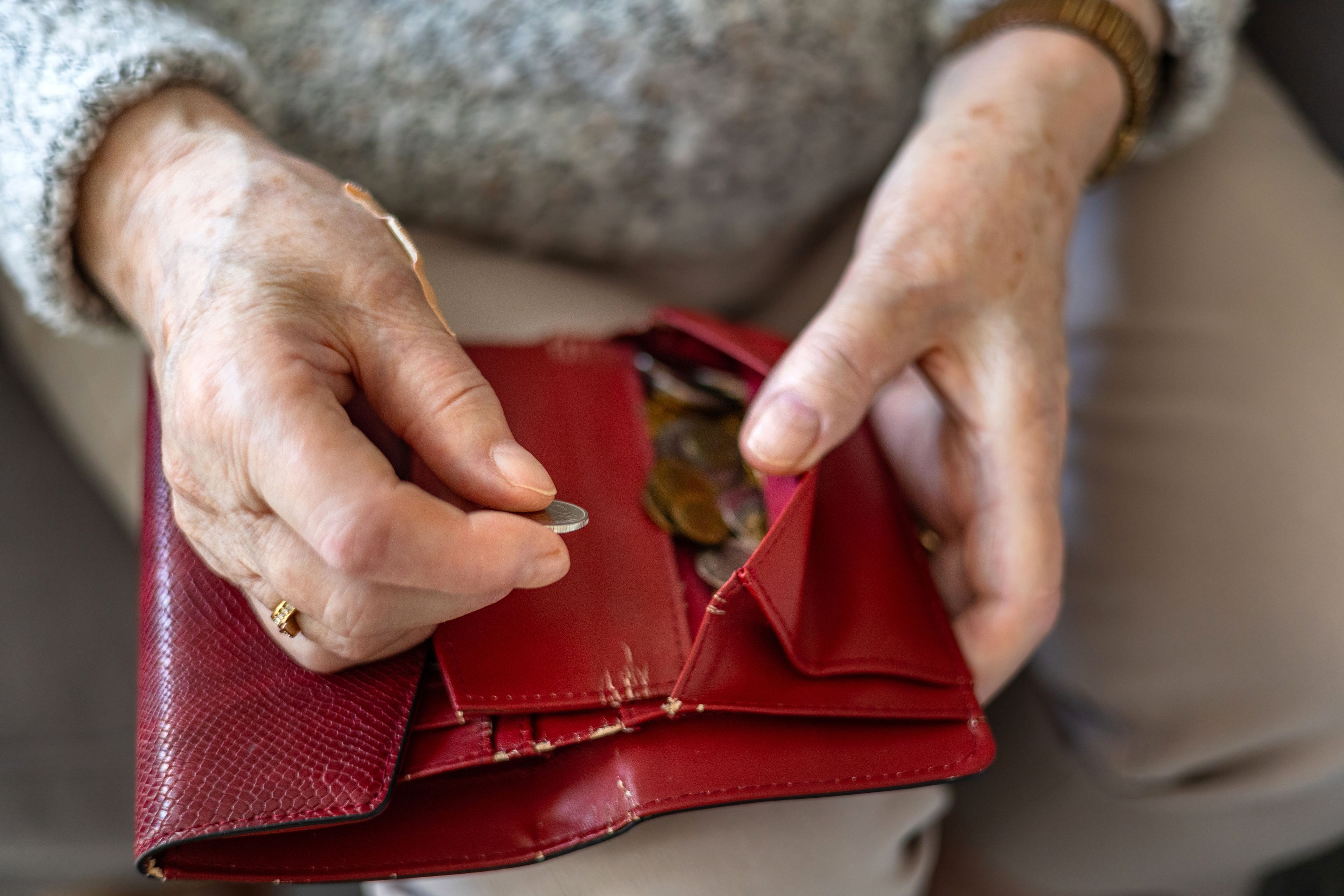 Una anciana sostiene una cartera con monedas | iStock
