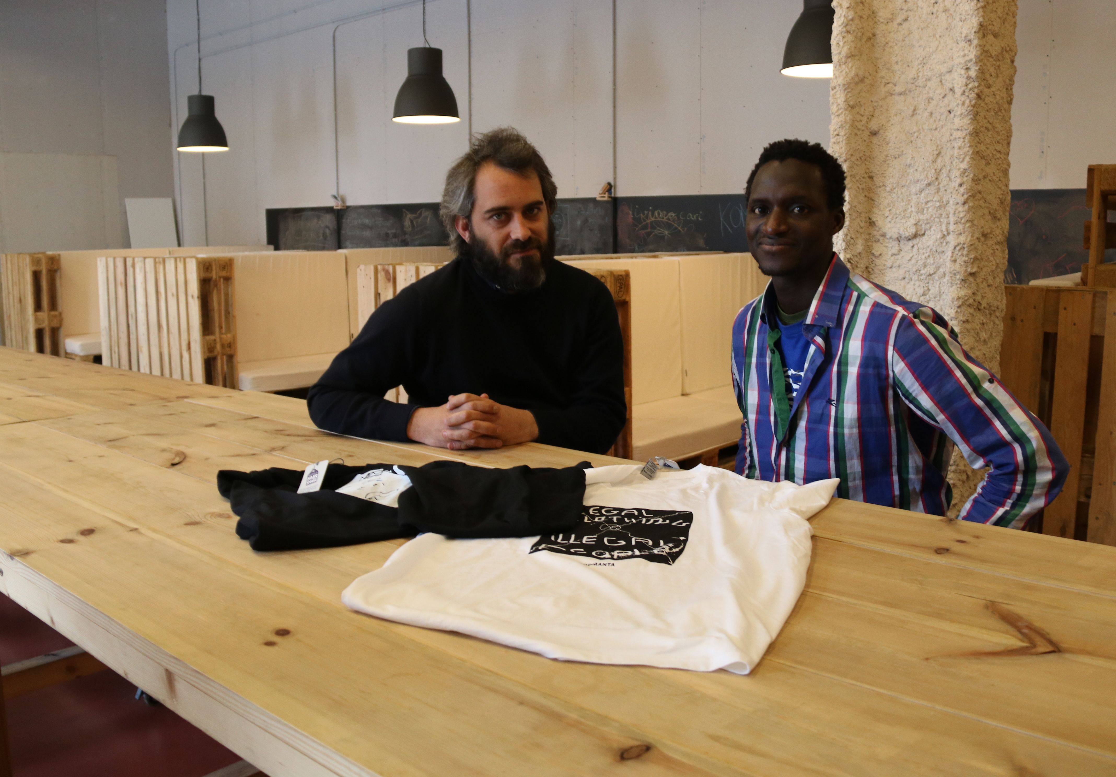 Cristian Palazzi, director de PlayGround Do, i Aziz Faye, membre del sindicat de manters, ensenyen les camisetes 'Top Manta' | ACN Cristian Palazzi, director de PlayGround Do, i Aziz Faye, membre del sindicat de manters, ensenyen les camisetes 'Top Manta' | ACN