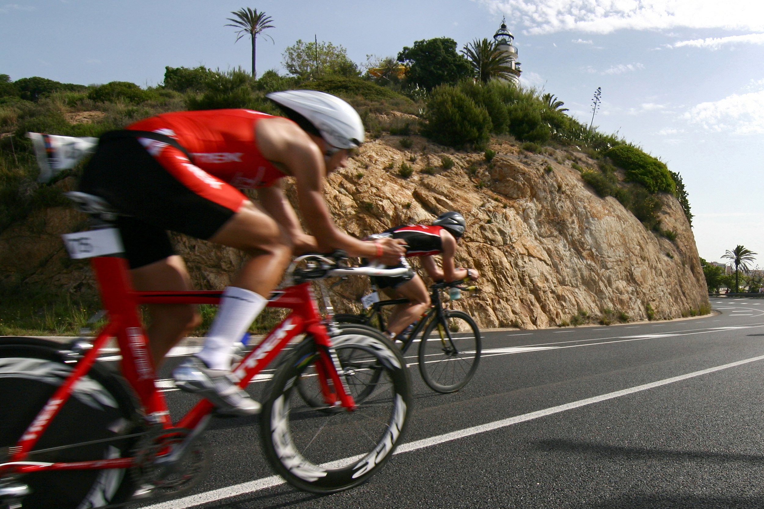 Un grup de ciclistes per la N-II, davant del Far de Calella.