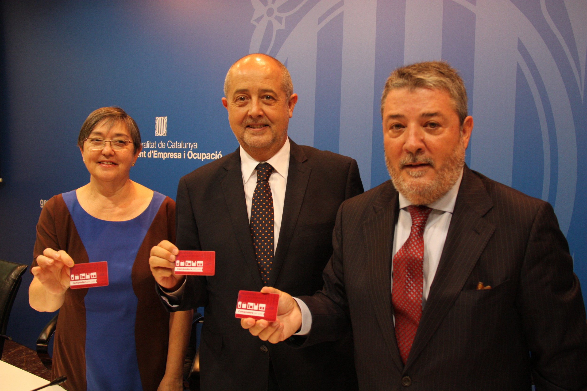 La presidenta de la Confederació de Comerç de Catalunya (CCC), Maria Rosa Eritja, el conseller d'Empresa i Ocupació, Felip Puig, i el secretari general de la CCC, Miguel Ángel Fraile, mostren la nova targeta de fidelització 'Compradors pel país' 